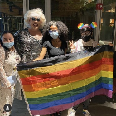 Students gather with a drag performer and a Pride flag at a student event