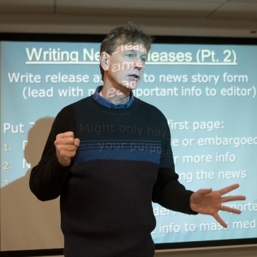 Communication's professor stands at the front of the class to give a lesson. 