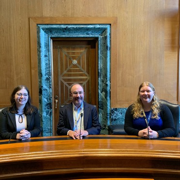 Congressional Interns Cassidy O’Connor ’23, Christine Belitsky’ 24 with Michael Evans ’76, former U.S. Senate Finance Committee Chief Counsel in US Senate Committee Room