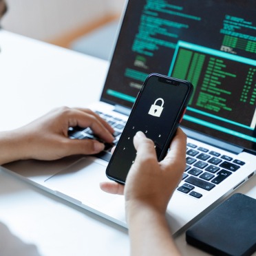 User on a laptop with a locked smartphone