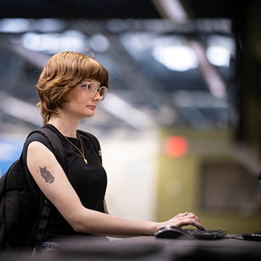 A female student logs into her Navigator account from a desktop computer station in the Student Navigation Center