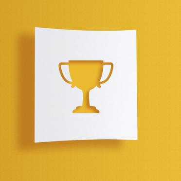 A white paper cut-out of a trophy against a yellow background.