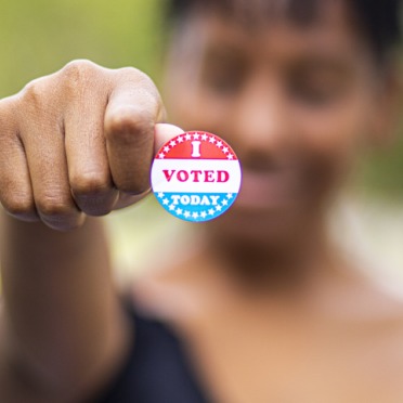 A woman holds up her "I Voted" sticker