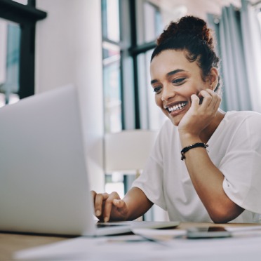 a woman sitting at a table looking at a laptop