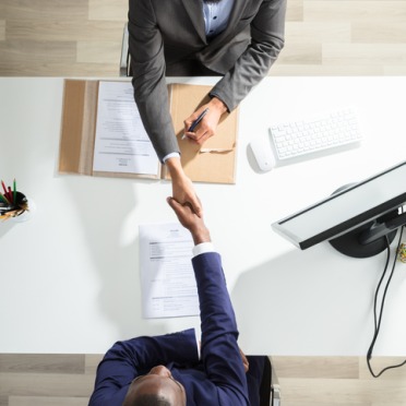 An overhead photo of two professionals shaking hands over a table.