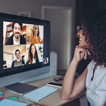 A woman smiling at a Zoom conference on screen