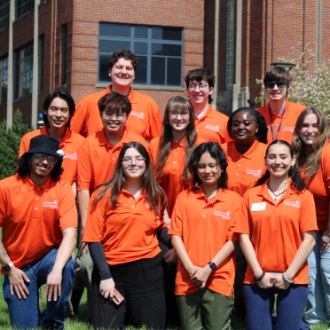 A group of orientation leaders in matching SSU polos pose outside the Classroom Building