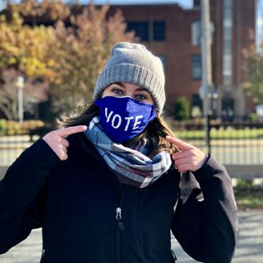 Student pointing to her mask that says "VOTE"
