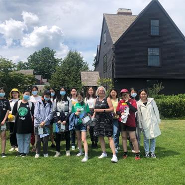 A group of international students pose in front of the house of seven gables