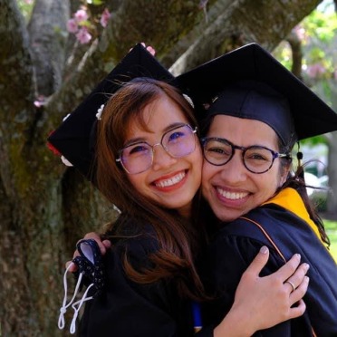 Two international students smiling and hugging at commencement