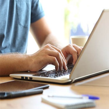 A male student types a paper on his laptop