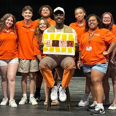Orientation leaders gathered on stage with a special guest speaker, smiling