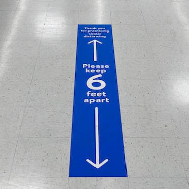 A floor cling encouraging people to stay 6 feet apart