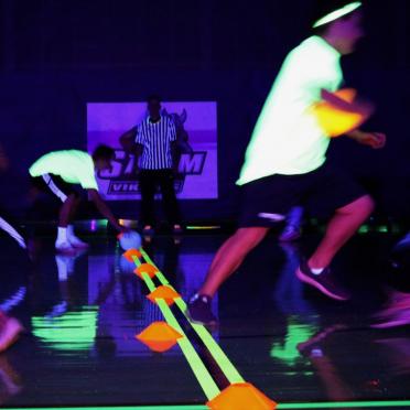 Closeup of two blacklight dodgeball teams in motion