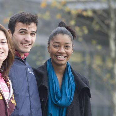 A group of students of diverse backgrounds enjoy a fall day on campus