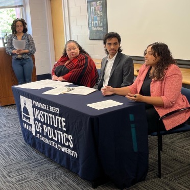 3 people sitting at a table in discussion