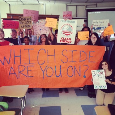 Students advocating for fossil fuel divestments hold painted signs on campus