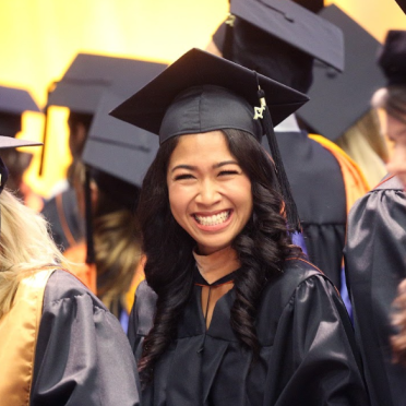 Female student in cap and gown smiling at Commencement