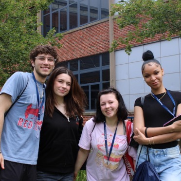 A group of four new students posing together outside of the Classroom Building