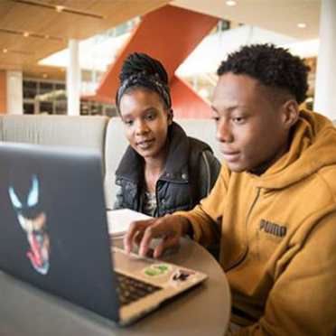 Two Salem State University students sit and work at a laptop.