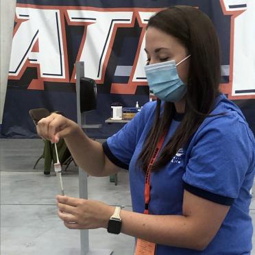A test-taker wearing a mask puts a swab into the test container