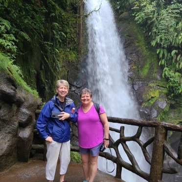Two faculty members stand next to a waterfall in Costa Rica