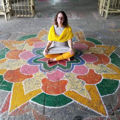 Emily Whipple sitting on mandala pattern painted on stone