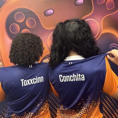 Two Esports players show off the back of their team jerseys.