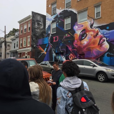 Students with backpacks exploring a city mural