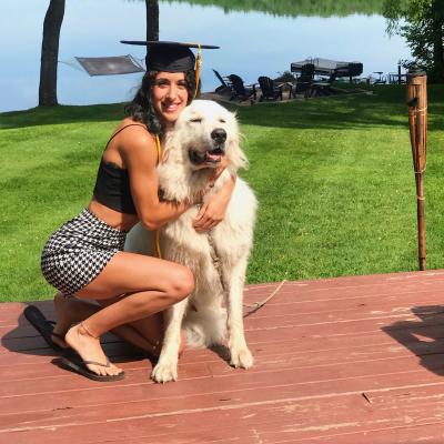 Paige Suse wears a graduation cap and hugs a dog.