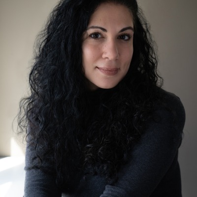 Susan Muaddi Darraj headshot smiling and wearing a dark sweater