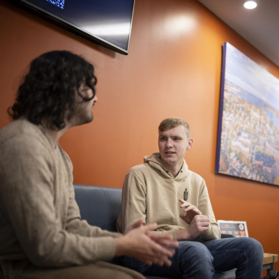 Two students chatting on a sofa in the lounge