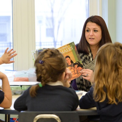 A female teacher facing a classroom of young students