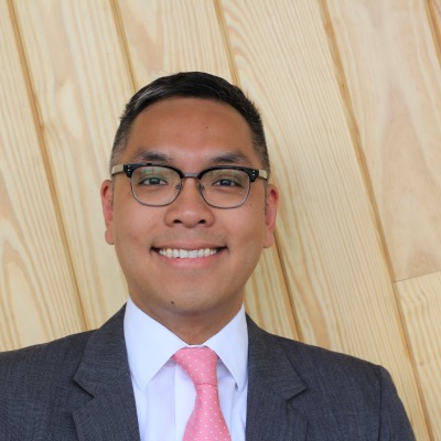 Image of a man in glasses and a suit with a pink tie