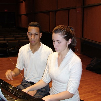 Two people sitting at a piano