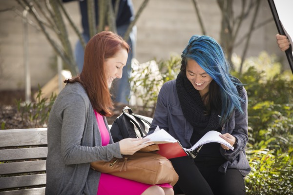 Two girls read a book together. 