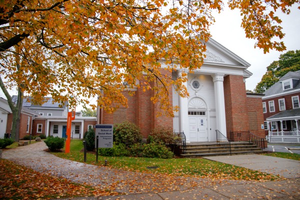 Social Work building with fall tree leaves in front of it.