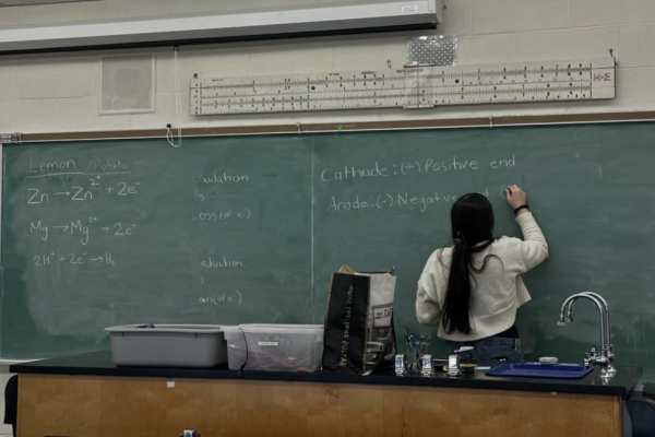A girl writes an equation on a chalk board
