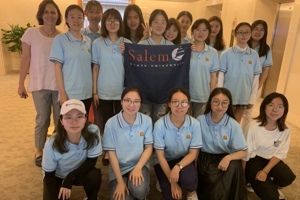 Chinese scholars visiting Salem State and holding the university flag