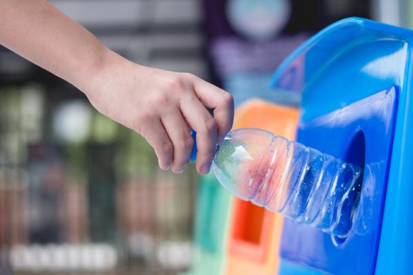 A student puts a plastic water bottle in the recycling bin