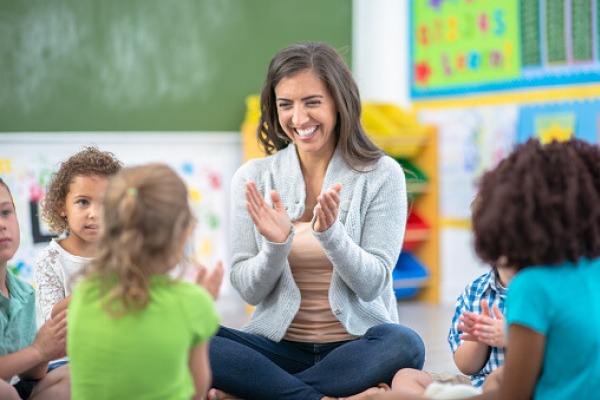 A young preschool teacher leads her students in a song