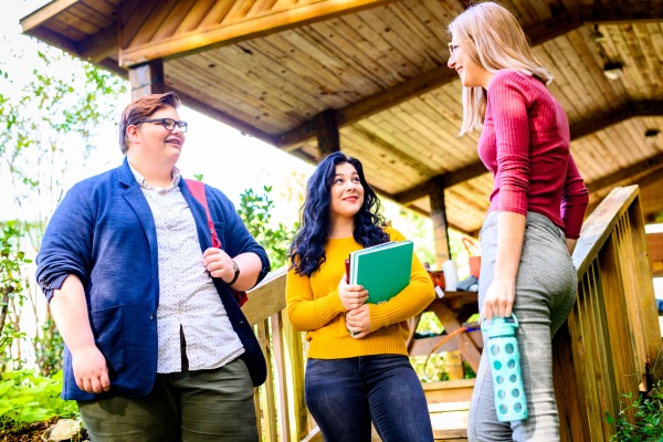 A group of three people outdoors smiling