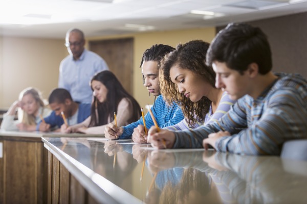 High school students at a table with a teacher in the background