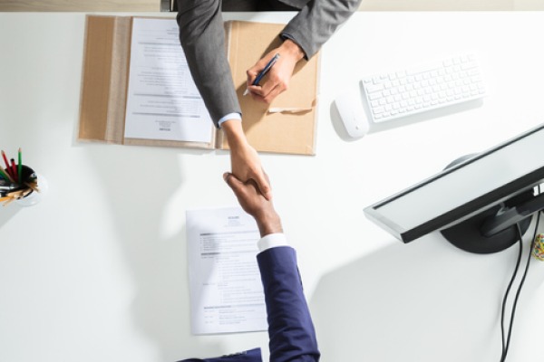 An overhead photo of two professionals shaking hands over a table.