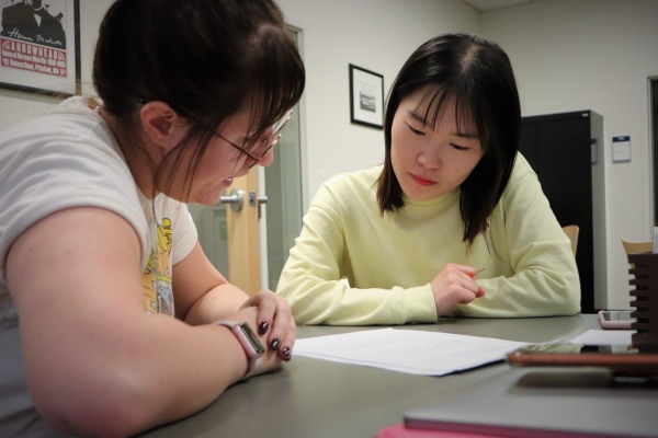 Two young women working at a table on a piece of writing