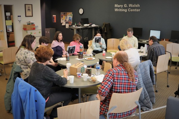 A group of students and tutors around a table in the writing center