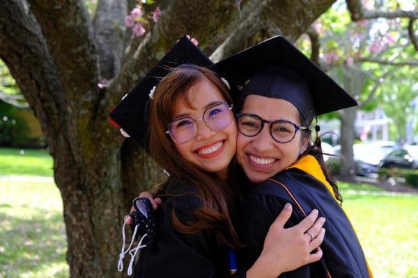 Two international students smiling and hugging at commencement
