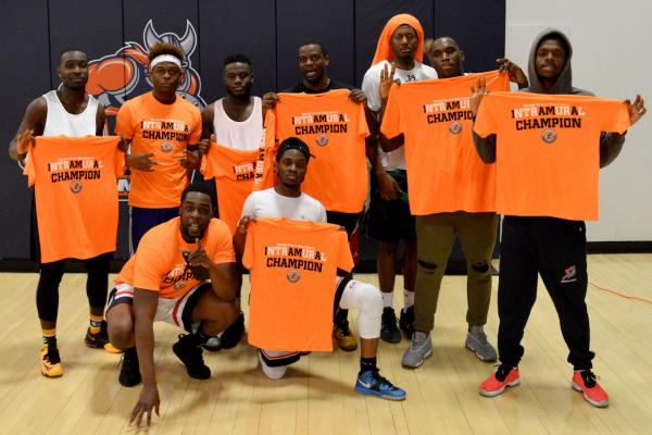 A group of students on the court holding up Intramural Chamption t-shirts