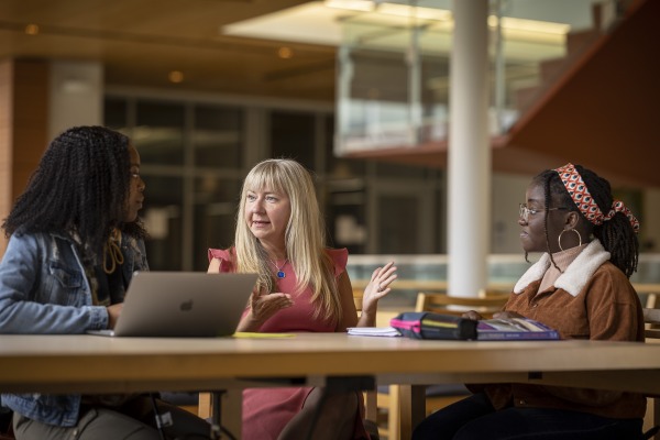 Faculty member Michele Louro sits in library with two students