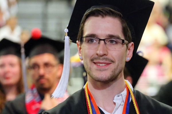 man in graduation gown and cap with honors cords